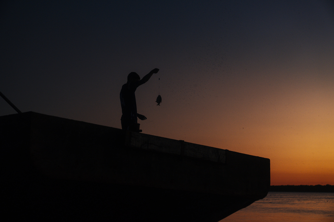 Silueta de pescador con el atardecer de fondo
